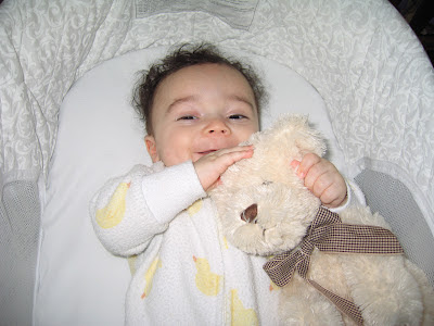 baby smiling and holding a teddy bear