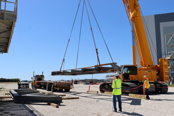 With the Vehicle Assembly Building visible in the background, steel trusses for Mobile Launcher 2 are unloaded at NASA's Kennedy Space Center in Florida.