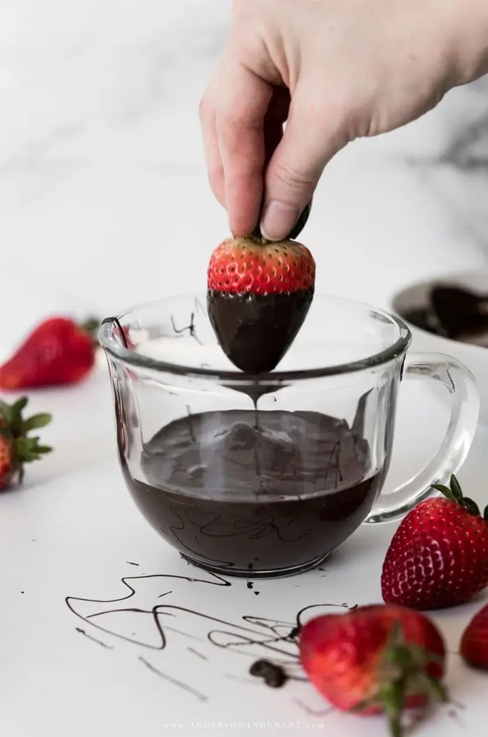 Dipping strawberry in mug of chocolate