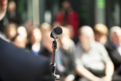 A microphone awaits you in front of a large audience