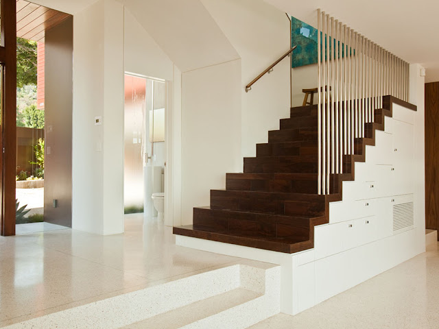 Picture of dark brown wooden staircase on the white concrete wall in the hallway