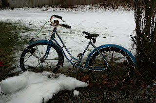 Old bicycle in the snow strunf with holiday lights