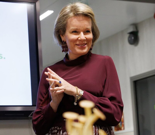 Queen Mathilde wore a burgundy silk top and burgundy printed silk skirt by Natan. Burgundy suede boots and clutch