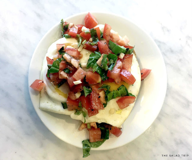 White plate on top of white marble with bruschetta on top of eggs and bread