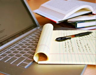 A notepad with pen on top which is then placed on keyboard of laptopp