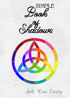 A photo of Jodi’s new book. A white and light gray mottled cover with the words “Simple Book of Shadows” written in nice lettering that’s easy to read. There is a rainbow mosaic digital art triquetra on the cover, surrounded by a circle.