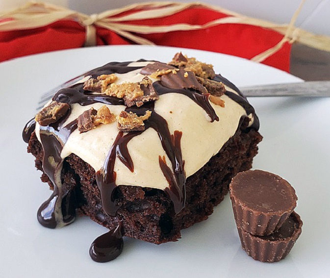 this is called a poke cake and is filled with chocolate peanut butter cream cheese frosting and whipped cream with hot fudge sauce on top and crumbled peanut butter cups