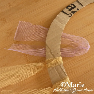 Tulle netting strips starting to tie around a cardboard base