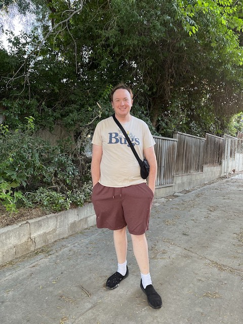 Man standing outside with school bag.