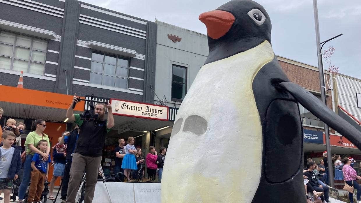 Một chú chim cánh cụt khổng lồ lạch bạch đi xuống đường George trong cuộc diễu hành ông già Noel hàng năm ở Dunedin năm 2022.