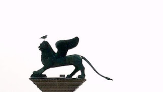 St. Mark's Lion, the symbol of Venice after 882, standing on its pedestal at the entrance to the Piazza San Marco, beside the Venetian Lagoon.