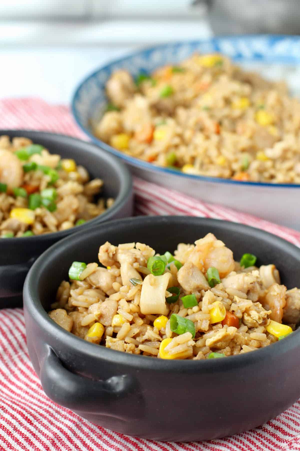 Chicken and Seafood Fried Rice in black bowls with the blue bowl in the background.