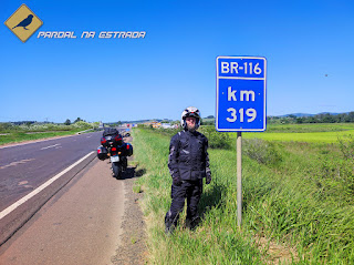 O escritor do blog ao lado da placa de KM 319 da BR-116 em Rio Grande do Sul com sua Honda CB500X ao fundo.