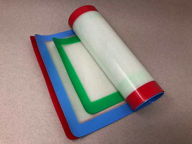 A set of 3 silicone baking mats partially rolled up