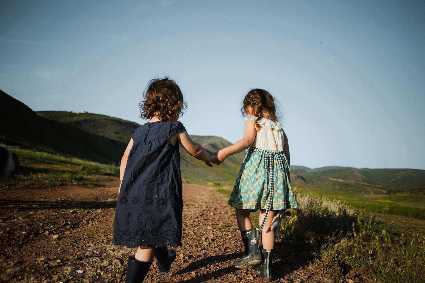 two girls holding hands going up mountain path - clothing your kids