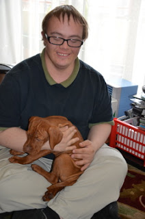 young man with Down syndrome holds vizsla puppy