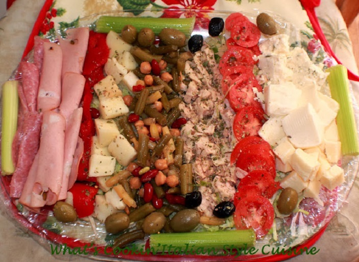 This is a cheese, wine, fruit, meats, beans, tuna, peppers, olives and board built or appetizer plate for Christmas Day  with all kinds of appetizers to include