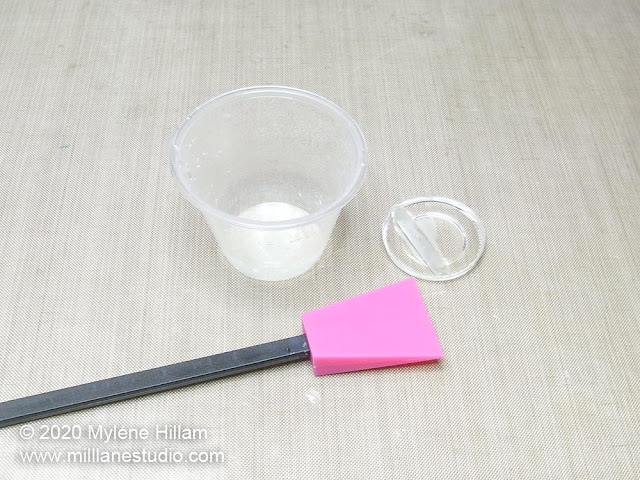 Polypropylene cup, silicone stirrer and a cured plug of resin sitting on a Teflon craft sheet