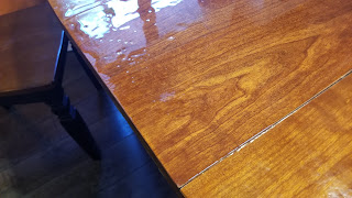 A photograph of part of a wooden table with a lumpy but glossy resin finish.