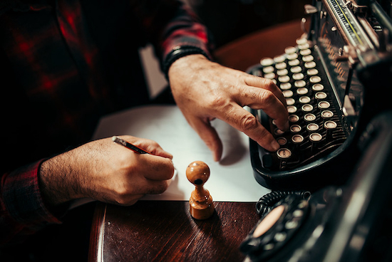 Image of person using an old typewriter and pen by Nenad Stojkovic and released under Creative Commons BY 2.0 DEED