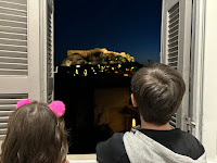 Two children looking through window at Acropolis, Athens, at night