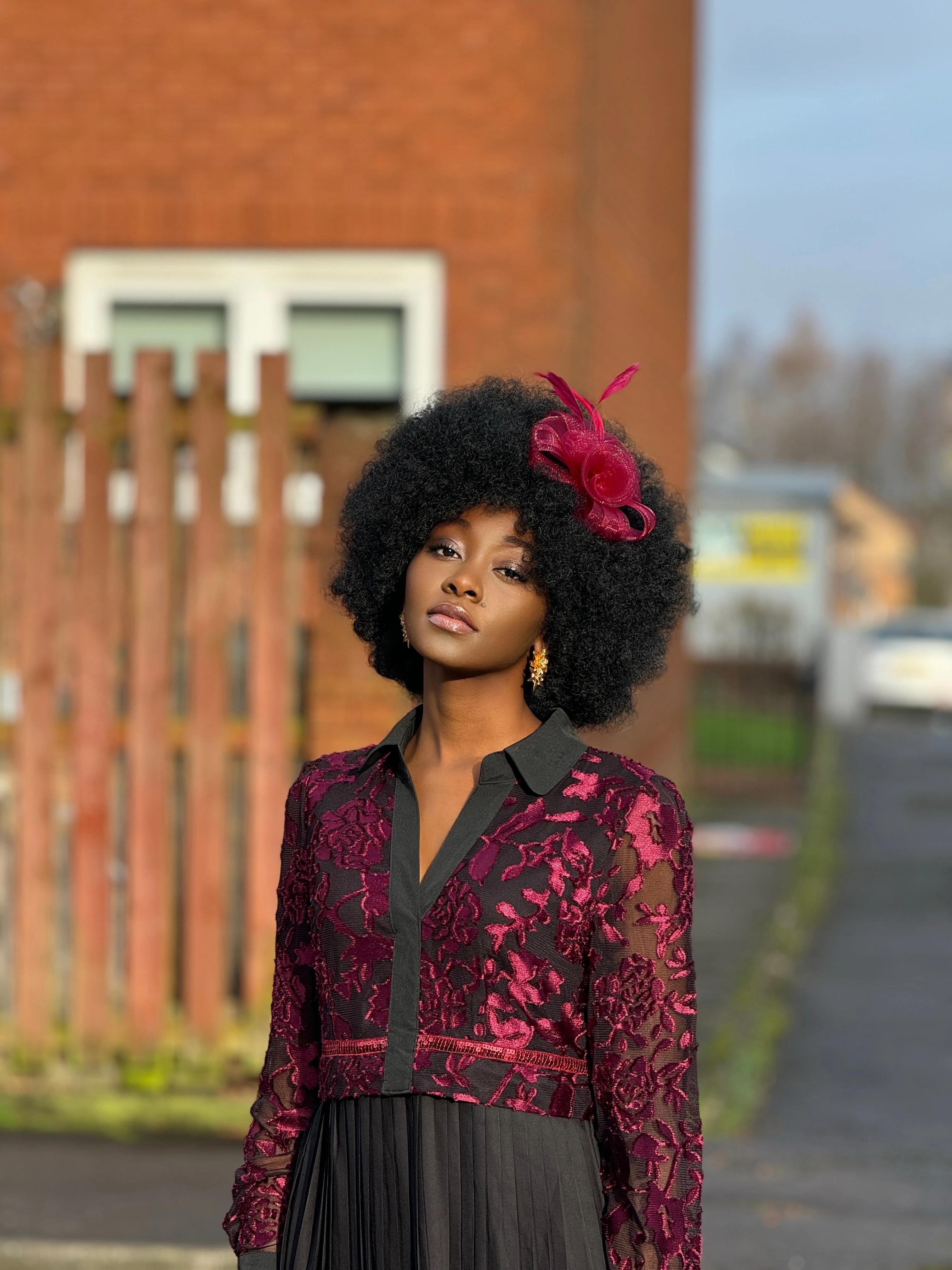 Woman looking chic and elegant in her burgundy berry fascinator from Quiz Clothing.