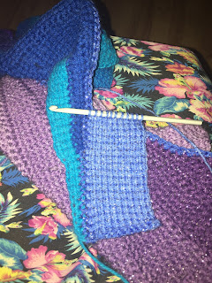 A rectangle of Tunisian crochet in a light blue yarn along the edge of a thin triangle of teal Tunisian crochet.