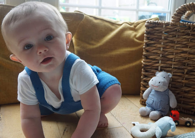 baby knelt on all fours and looking to camera