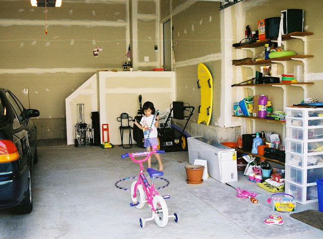 little girls playing in garage with a little bike and toys