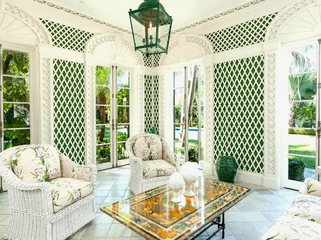 Sun room in a Palm Beach estate with wicker furniture and white and green trellis walls