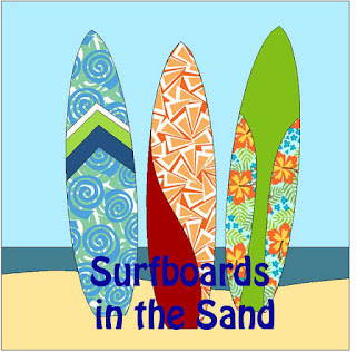 three different colorful surfboards standing up in the sand with an ocean behind