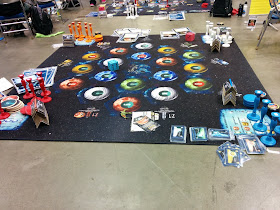 An oversized playset of Star Trek Catan. The board has been printed on a ten foot by ten foot carpet, and there are oversized cards and playing pieces around the edge of the board.