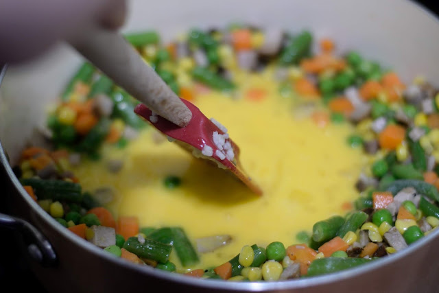 The eggs being scrambled in the pan with a rubber spatula.  