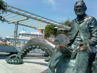 The statue in honor of the French novelist Jules Verne and his book "20,000 miles under the sea" and in the background, the cruiser "Queen Mary 2" docked in the port of Vigo (E.V.Pita, 2012)