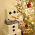 Muñeco de nieve cuadrado para los regalos junto al árbol