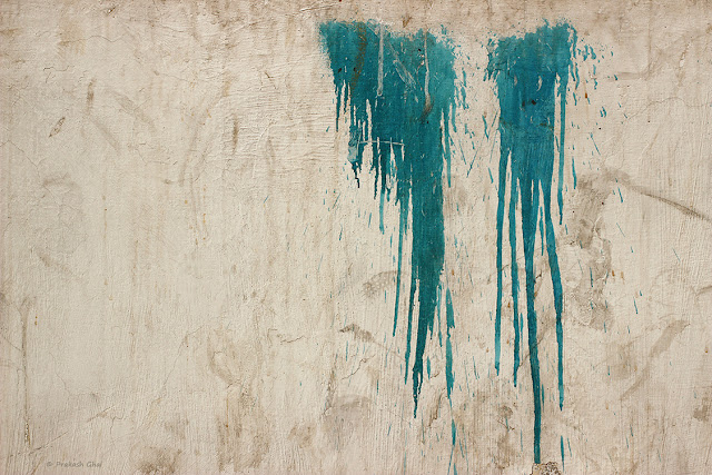 A Minimalist Photo of Two patches of dripping blue paint on a textured Indian wall