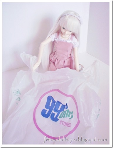 A ball jointed doll peeking in a 99 Cents Only Store shopping bag to see what's inside.