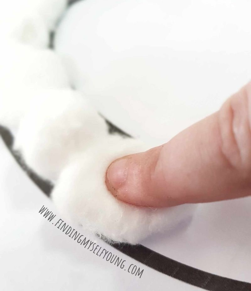 finger pressing down on cotton ball