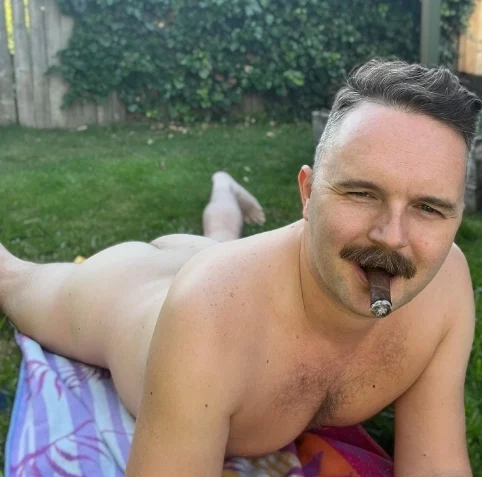 Laying in the grass naked ass up smoking a cigar