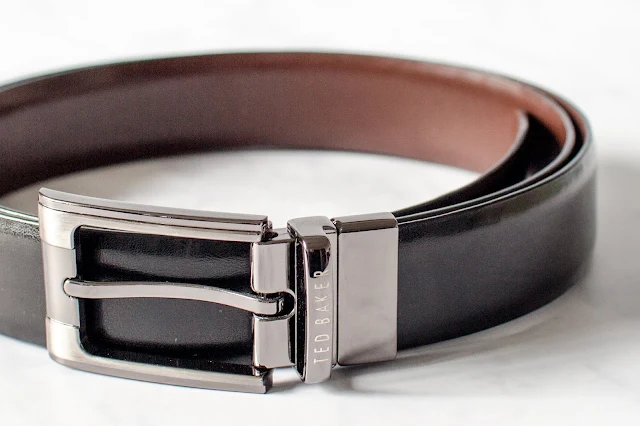 A close up image of a ted baker leather belt with silver buckle and reversible black and brown long belty bit