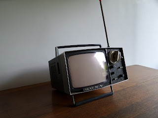 A vintage Sony portable television sits on a wooden surface.