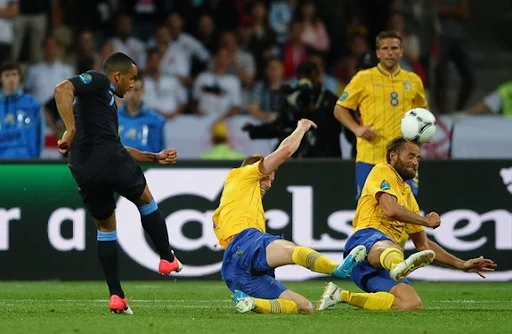 English player Theo Walcott kicks the ball to score a goal against Sweden