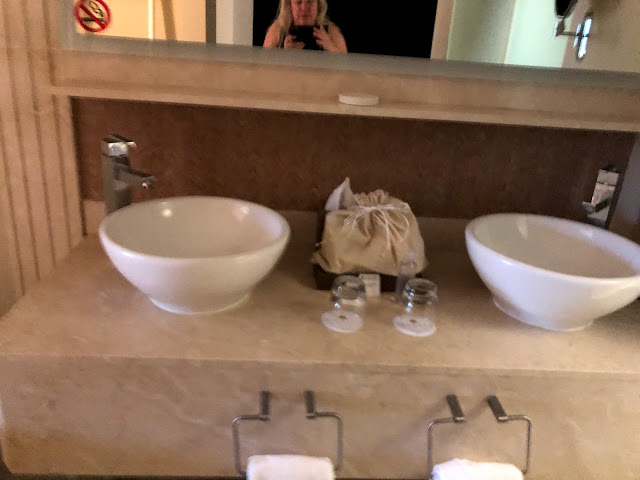 Dual sinks in a vanity, a sack of toiletries is between the sinks