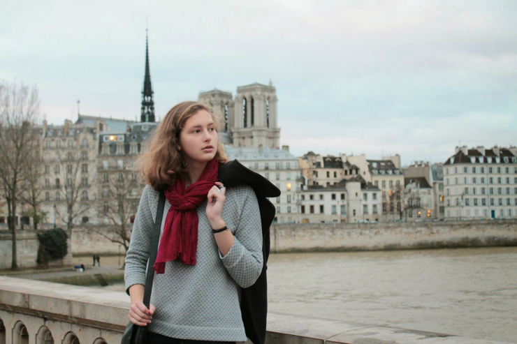 Parisian style of black pea coat, fashionable sweatshirt and jeans with a black leather bag