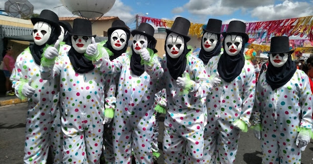 foto de papangus com roupas de bolinhas, cartola preta e máscara branca