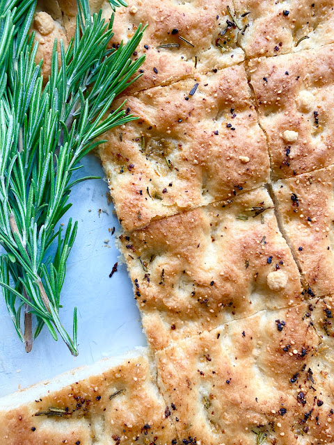 Pan of sliced focaccia bread with sprigs of fresh rosemary.