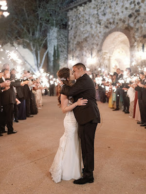 bride and groom kissing between sparklers at night