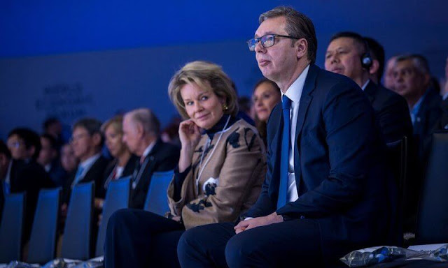 Queen Mathilde wore an embroidered coat by Esmeralda Ammoun, and poppy gold small earrings by Christine Bekaert