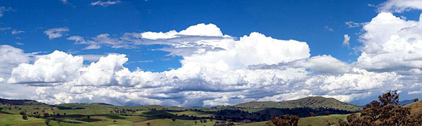 panoramic view of clouds in blue sky over green landscape