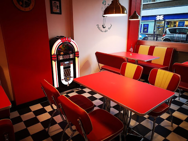 Interior of Lily's American Diner in Folkestone, with red and white walls, leather chairs, chequerboard flood and a jukebox
